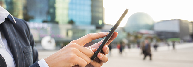 Businesswoman using her mobile phone in front of Building