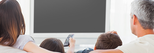 Family sitting on sofa watching television together